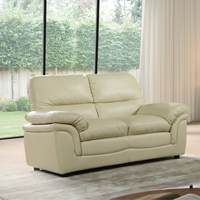 Beige leather sofa in a living room with large windows and curtains.
