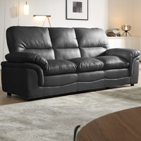 Grey leather sofa in a living room setting with a rug and table.