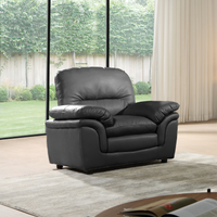 Black leather recliner chair in a room with large windows and curtains.