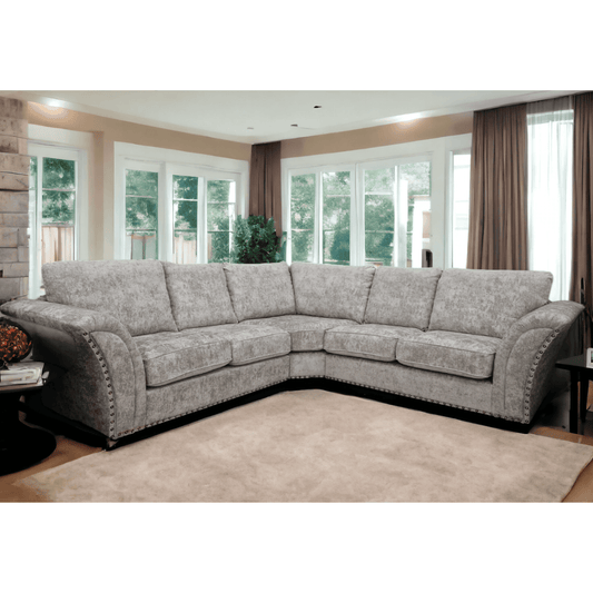 Gray sectional sofa in a living room with large windows and curtains.