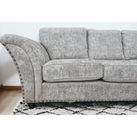 Gray sofa with nailhead trim on a white wall background