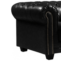 Close-up of a black leather armchair with tufted backrest and nailhead trim on a white background.