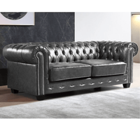 Gray tufted sofa in a room with a dark wall and light floor.