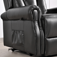 Close-up of a black leather recliner chair with power button on a light wooden floor.