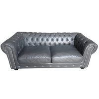 Gray leather sofa with tufted backrest on a white background
