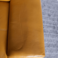Close-up of a yellow leather couch corner on a gray carpet