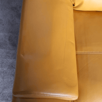 Close-up of a yellow leather sofa with a textured gray background