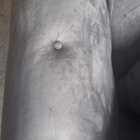 Close-up of a gray upholstered arm or cushion with a tufted button detail and textured fabric.