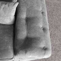 Gray cushion with tufted design on a textured surface