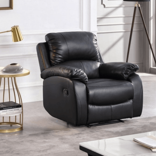 Black leather recliner chair in a living room setting with a side table and lamp.