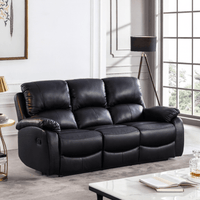 Black leather sofa in a living room setting with a lamp and table.