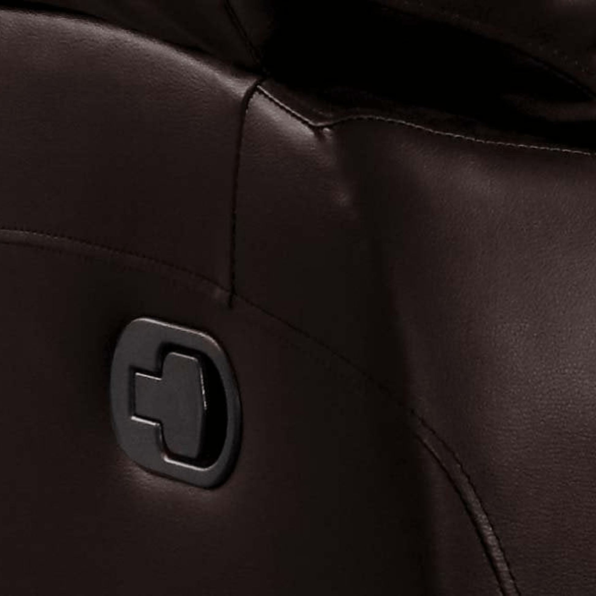 Close-up of a black leather surface with a metallic logo.
