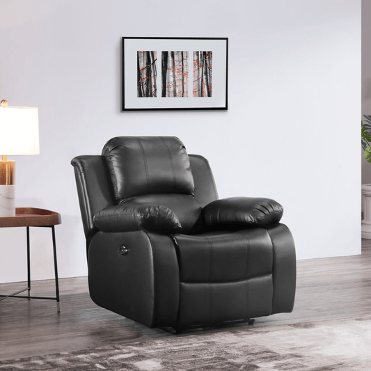 Black leather recliner chair in a living room setting with a lamp and framed picture on the wall.