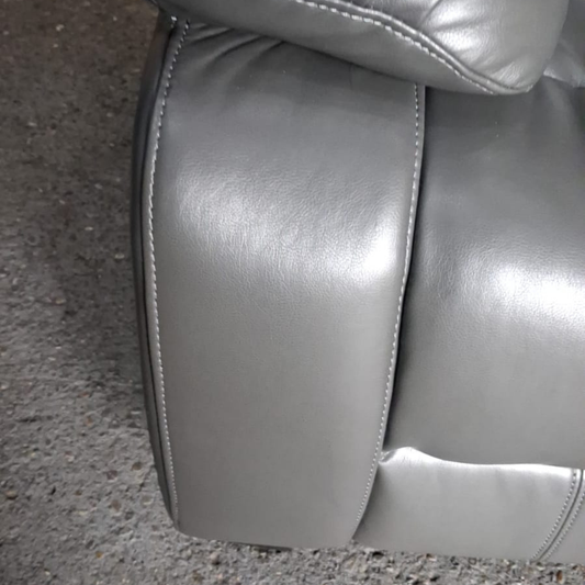 Close-up of a gray leather car seat on a concrete floor.