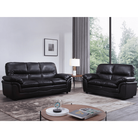 Black leather sofa set in a living room with a coffee table and decor items.