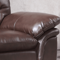 Brown leather recliner chair against a neutral wall.