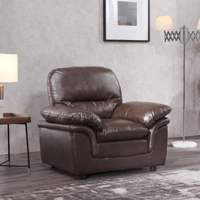 Brown leather recliner chair in a living room setting with a lamp and framed picture on the wall.