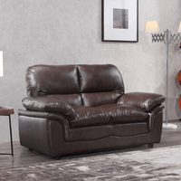 Brown leather sofa in a living room setting with a lamp and wall art.