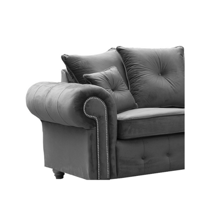 Grey velvet sofa with tufted backrest and decorative pillows on a white background