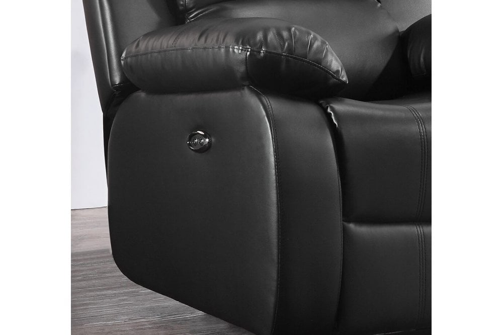 Close-up of a black leather recliner chair with a button on a wooden floor.