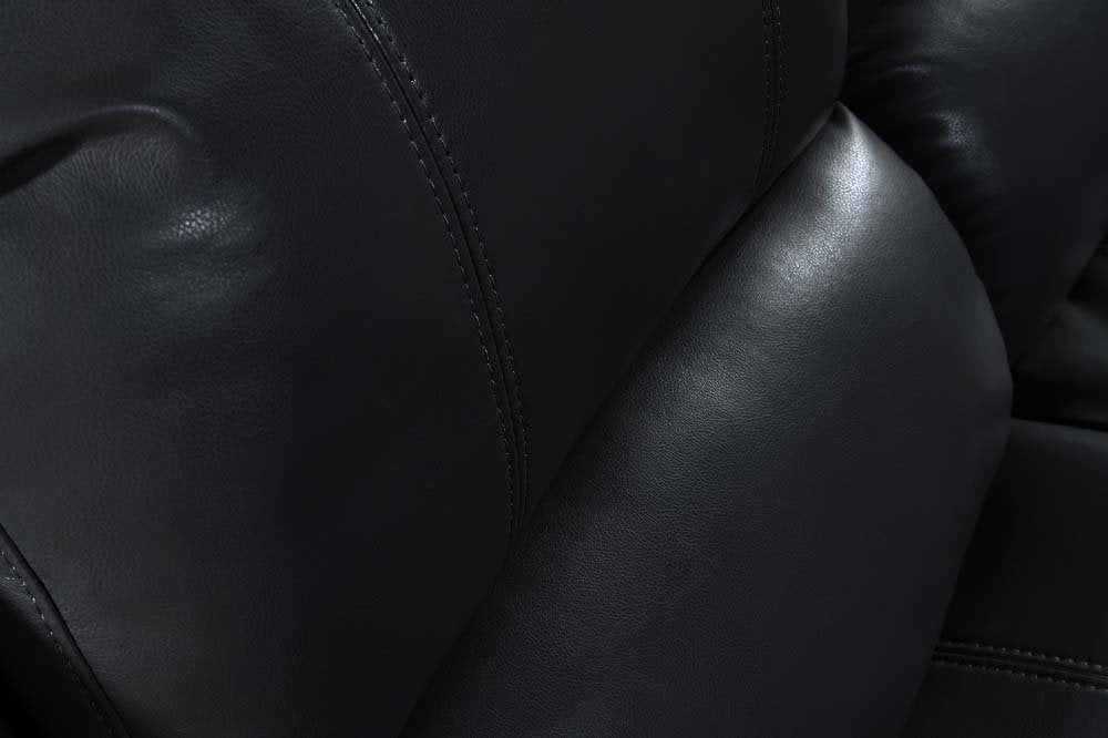 Close-up of a black leather surface with visible texture and stitching.