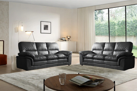 Modern living room with black leather sofas and a round wooden coffee table.