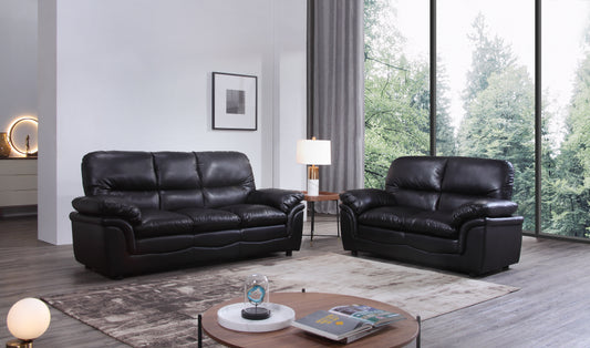Black leather sofa set in a modern living room with large windows.