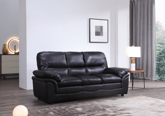 Black leather sofa in a living room setting with a lamp and framed picture on the wall.