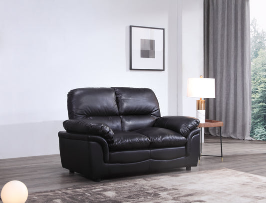 Black leather sofa in a modern living room with a lamp and framed picture.