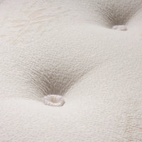 Close-up of a white tufted mattress or upholstered surface with visible stitched button tufts and a textured dotted fabric pattern.