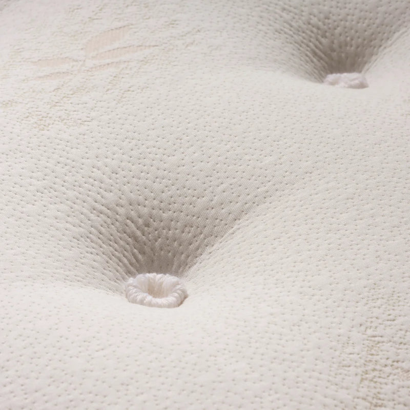 Close-up of a white tufted mattress or upholstered surface with visible stitched button tufts and a textured dotted fabric pattern.