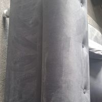 Close-up of a dark gray tufted upholstered headboard or chair back with visible button tufting and fabric texture.