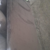 A close-up view of a dusty brown upholstered armrest or sofa section, showing visible scuffs and dirt marks on the surface, next to a textured gray carpet.
