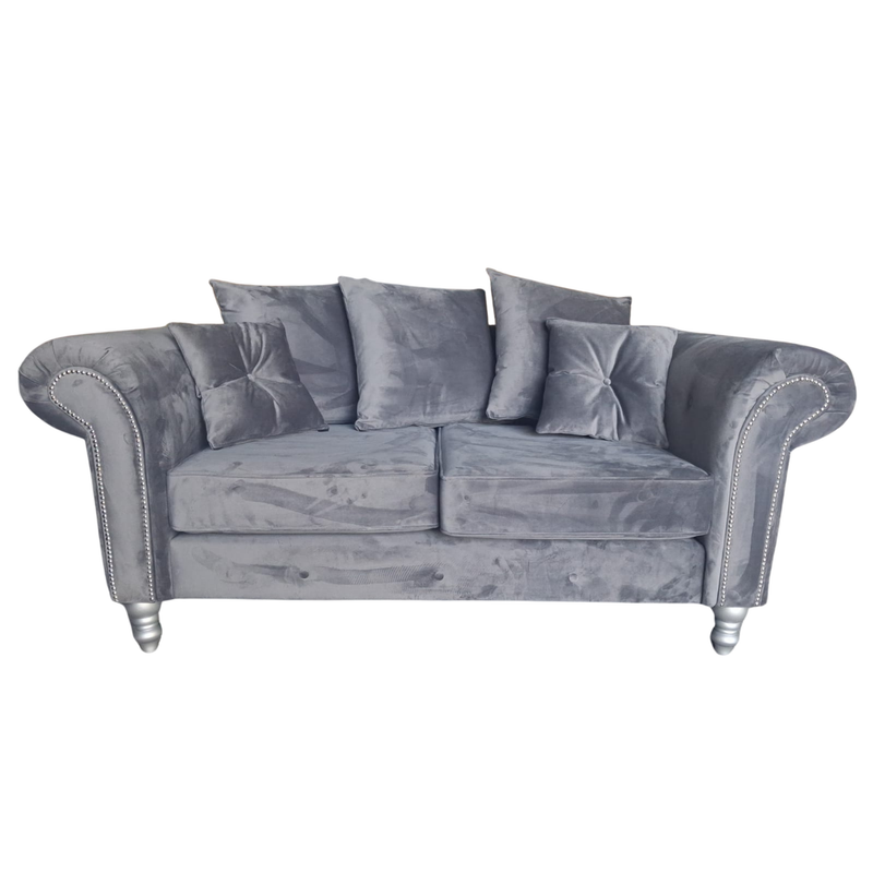 A gray velvet loveseat sofa with rolled arms, silver nailhead trim, and matching gray throw pillows, shown against a plain white background.