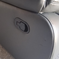 Close-up of a gray upholstered recliner chair showing the side adjustment control and part of the seat cushion.