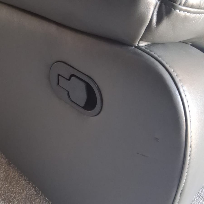 Close-up of a gray upholstered recliner chair showing the side adjustment control and part of the seat cushion.