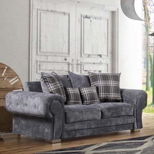 Gray sofa with plaid cushions in a room with wooden floor and white walls.