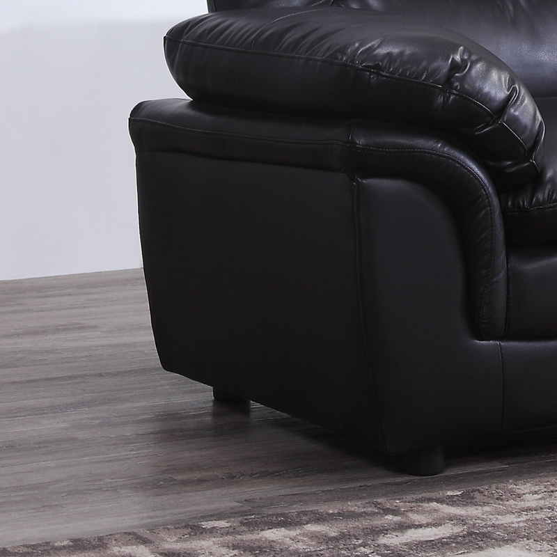 Black leather sofa on a wooden floor with a white wall background