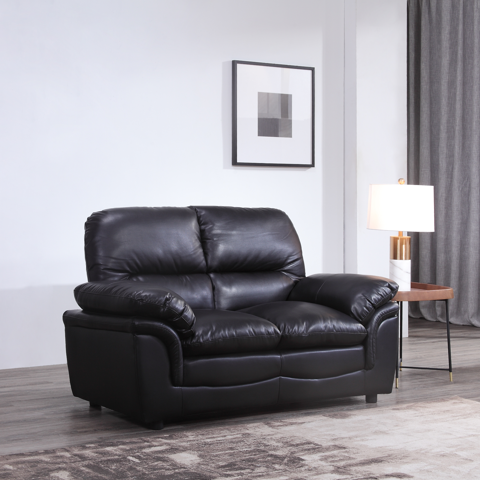 Black leather sofa in a living room setting with a lamp and wall art.