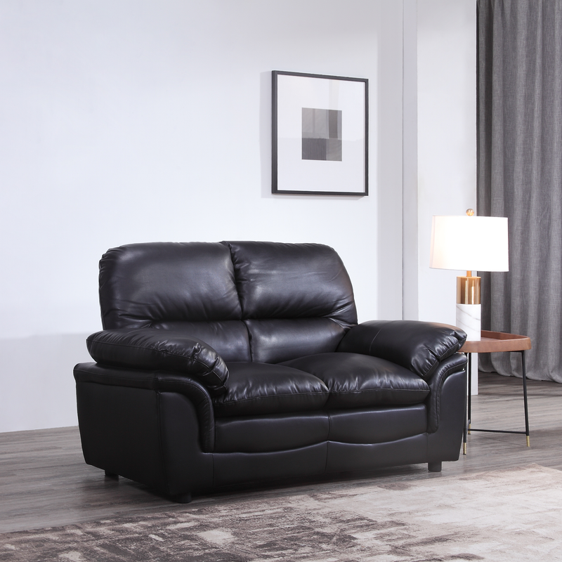 Black leather sofa in a living room setting with a lamp and wall art.