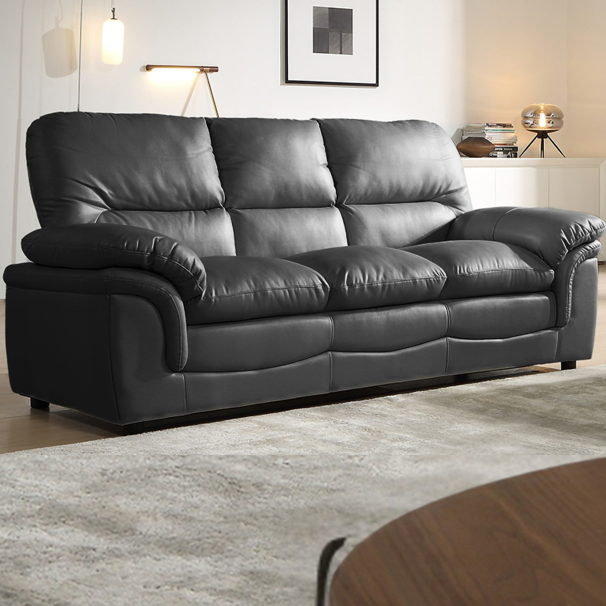 Gray leather sofa in a living room setting with a rug and table.