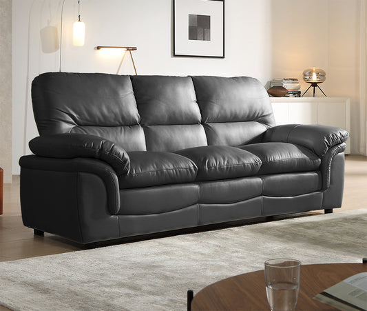 Gray leather sofa in a living room setting with a table and decor items.