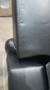 Close-up of a black leather seat with visible stitching on a vehicle.