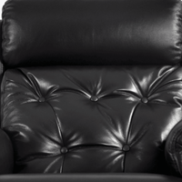 Close-up of a black leather armchair with buttoned backrest