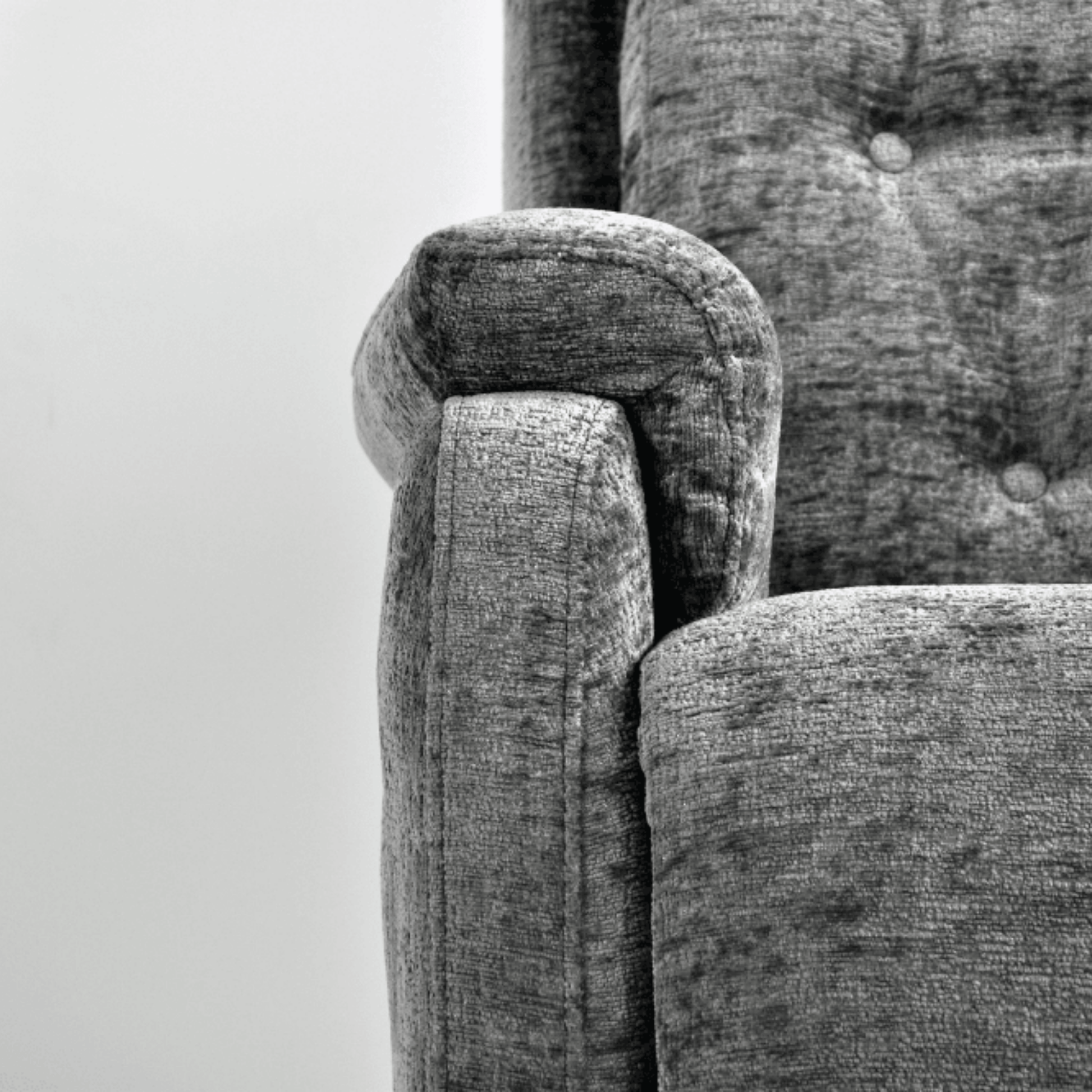 Close-up of a textured gray fabric surface with a chair corner.