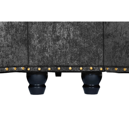 Close-up of a gray upholstered chair with black legs and gold studs on a white background