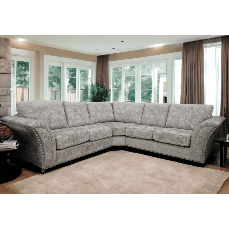 Gray sectional sofa in a living room with large windows and curtains.
