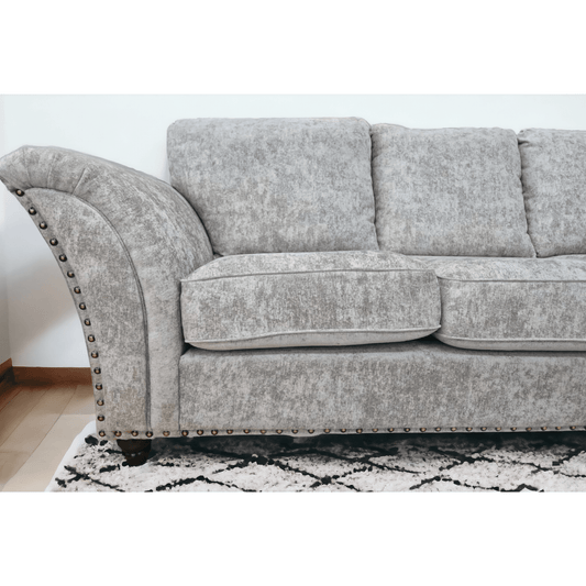 Gray sofa with nailhead trim on a white wall background