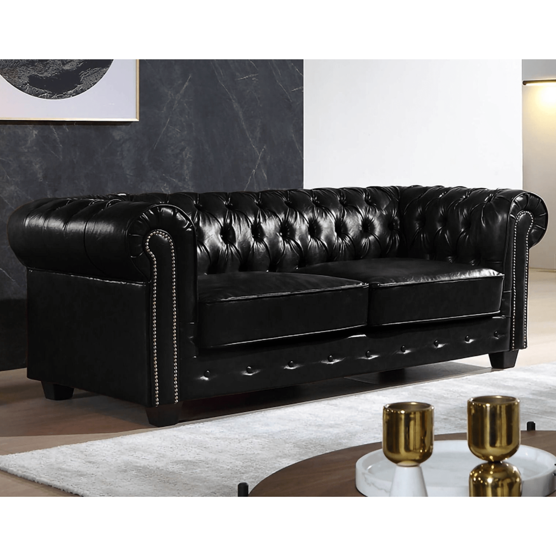 Black leather Chesterfield sofa in a living room setting with a coffee table and decor items.