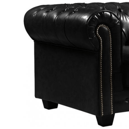 Close-up of a black leather armchair with tufted backrest and nailhead trim on a white background.